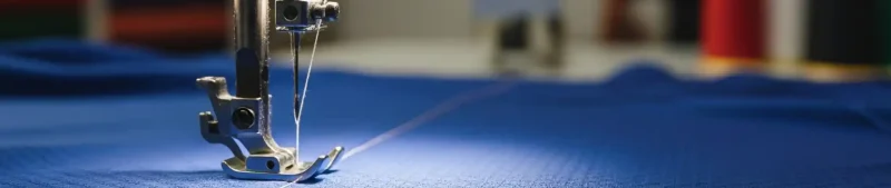 Custom apparel makers in Kerala – close-up of sewing machine during stitching process